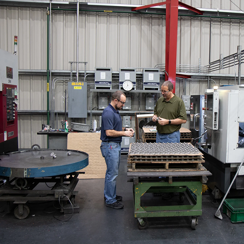 Two men inspecting part in warehouse