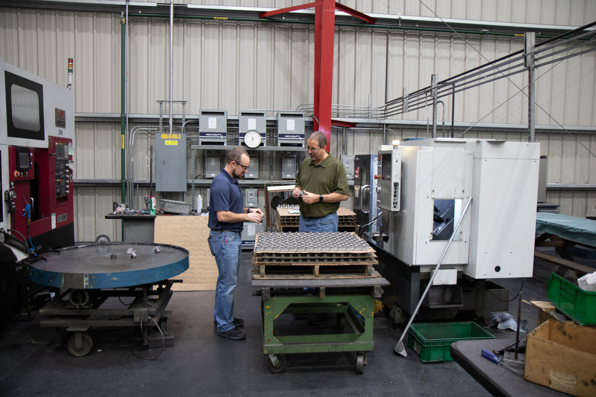 Two men in machine shop inspecting components